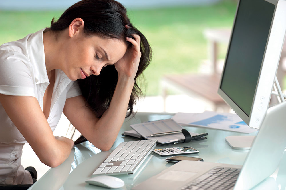 vrouw aan computer met de handen in het haar