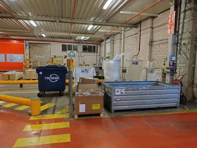 In een afgebakende plek in de loods staan verschillende containers en bakken om materialen te recycleren