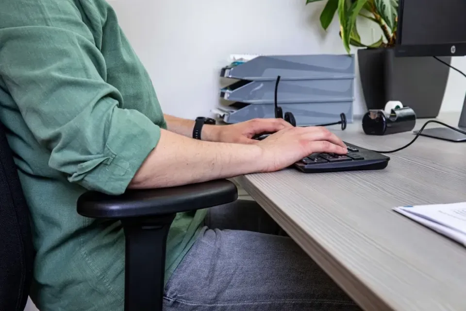 Werknemer zit in ergonomische houding aan zijn werkplek