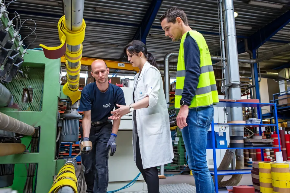 Vrouwelijke arbeidsarts en mannelijke preventieadviseur bij mannelijke werkgever in een industrieel bedrijf