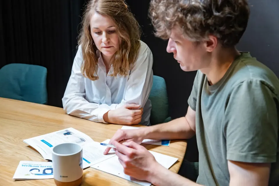Twee personen bespreken de terugkeer na werk na ziekteafwezigheid