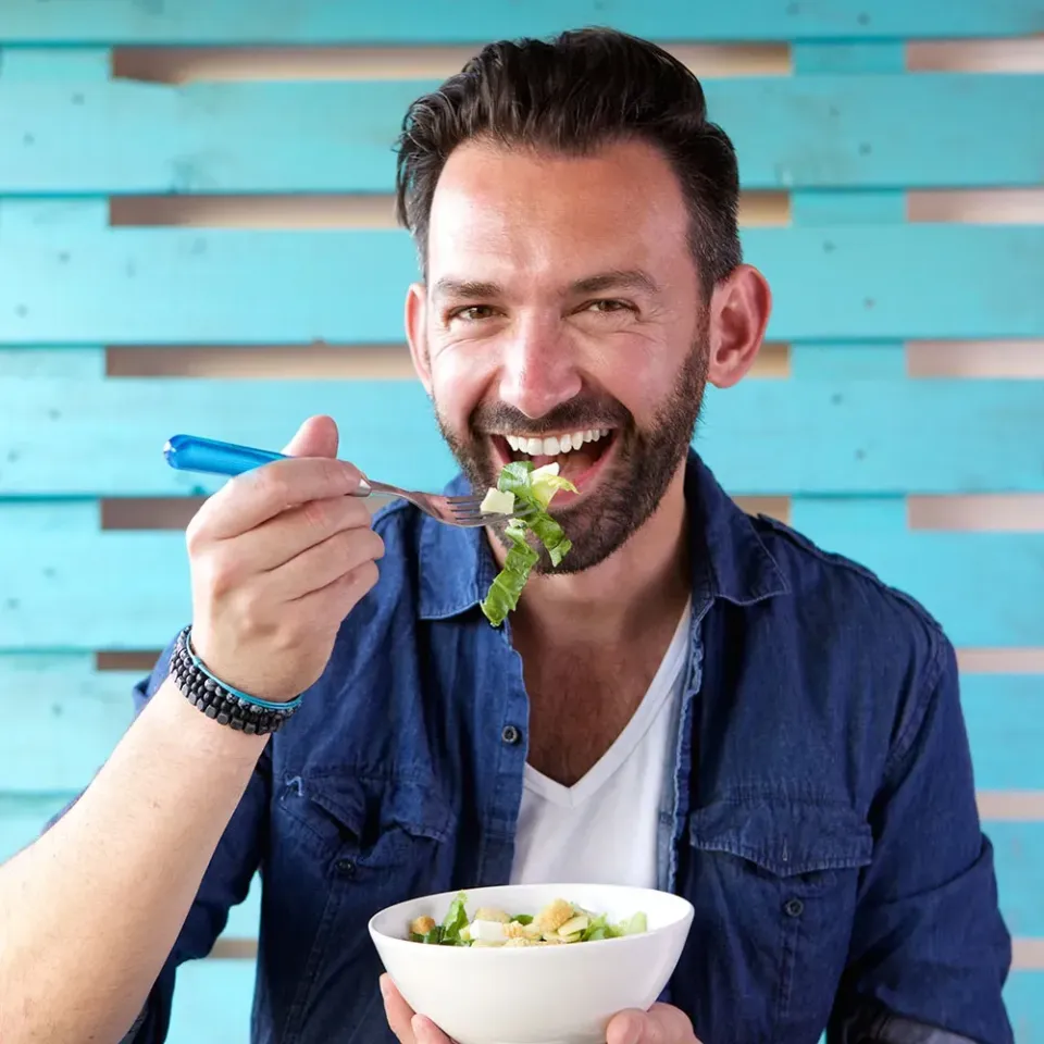 man eet salade uit een kommetje