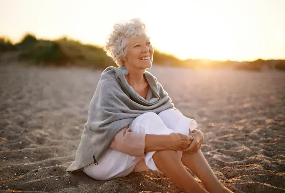vrouw genietend op het strand bij een ondergaande zon